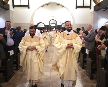 Father Samuel Rendon, left, and Father Juan Mendez, right, smile while people in the sanctuary applaud as the newly ordained priests process out of St. Francis of Assisi Catholic Church in Frisco on May 18. Bishop Edward J. Burns was the main celebrant for the Mass for the ordination of Father Rendon, Father Mendez, Father William Henry Mobley, and Father Parker Joseph Thompson at the Frisco parish. (Michael Gresham/The Texas Catholic)