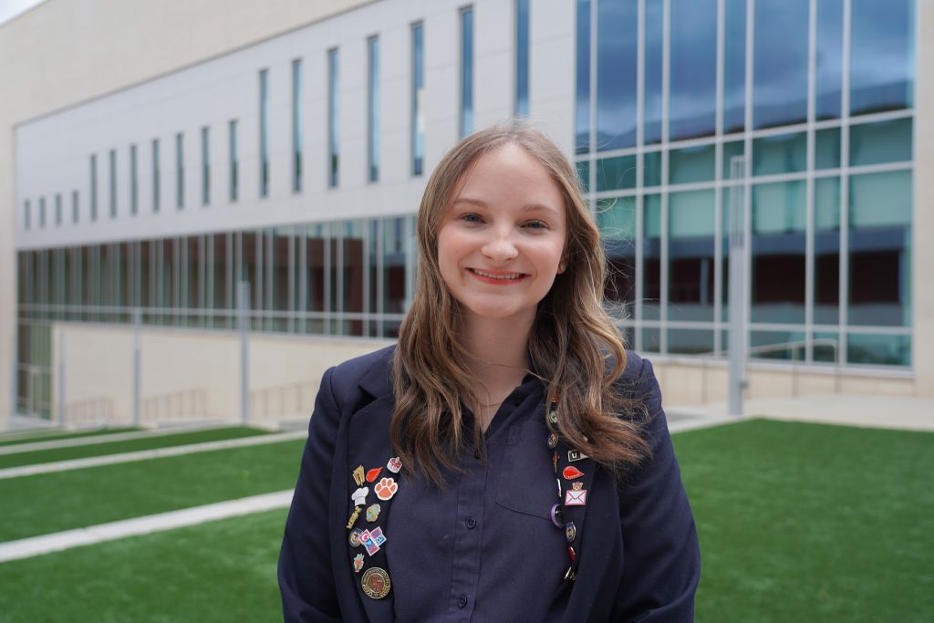 Ursuline Academy of Dallas graduate smiles as she stands on her school's campus