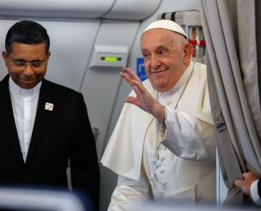 Pope Francis smiles and waves to journalists aboard his overnight flight from Rome to Jakarta, Indonesia.