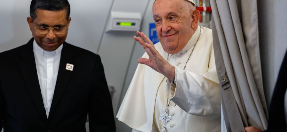 Pope Francis smiles and waves to journalists aboard his overnight flight from Rome to Jakarta, Indonesia.