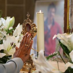 A pilgrim touches the reliquary containing a relic of the heart of Blessed Carlo Acutis.