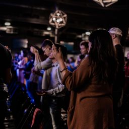 Young adults raise their hands in praise.