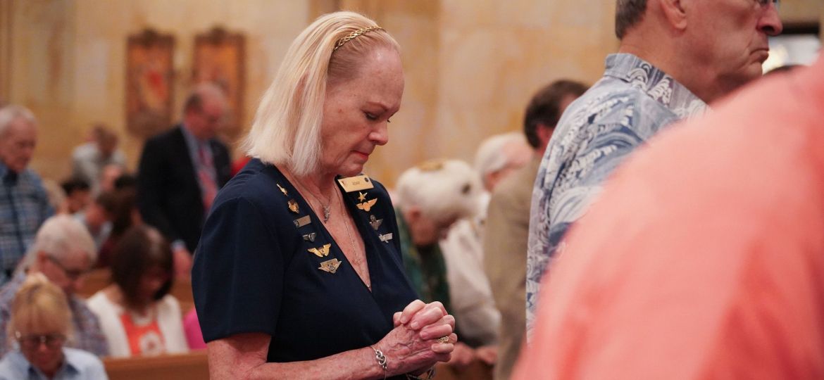 Elizabeth Adair Ahrens bows her head for a blessing during the Diocese of Dallas' inaugural Aviation Mass.