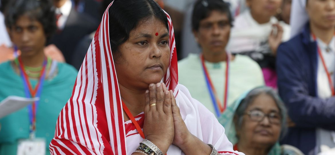 A woman folds her hands in prayer