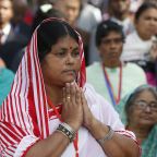 A woman folds her hands in prayer