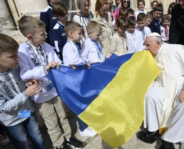 Pope Francis kisses a Ukrainian flag carried by a group of Ukrainian children attending his weekly general audience in St. Peter's Square at the Vatican April 10, 2024. The pope prayed during the audience for peace in Ukraine, in the Holy Land and in Myanmar. (CNS photo/Vatican Media)