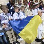 Pope Francis kisses a Ukrainian flag carried by a group of Ukrainian children attending his weekly general audience in St. Peter's Square at the Vatican April 10, 2024. The pope prayed during the audience for peace in Ukraine, in the Holy Land and in Myanmar. (CNS photo/Vatican Media)