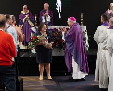 At the conclusion of the closing Mass for the Diocese of Dallas Synod Assembly, Bishop Edward J. Burns joins delegates, staff, and volunteers in applause as Lacy de la Garza accepts a bouquet of roses in appreciation of her efforts as the executive director of the synod. Two hundred and eighty-four delegates from around the diocese gathered Dec. 1-4 at the Dallas-Fort Worth Marriott hotel in Irving to offer a consultative vote on 376 synodal resolutions presented to Bishop Burns for consideration. (Michael Gresham/The Texas Catholic)