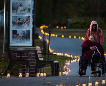 An elderly woman in a wheelchair is assisted around the candlelit path at the National Shrine of Our Lady of Champion in Champion, Wis., on Oct. 8, 2024. A rosary procession around the shrine grounds took place later in the evening. The procession is a yearly event that commemorates the "Great Fire of 1871," the most devastating forest fire in American history that swept through northeast Wisconsin, claiming around 1,200 lives.  Residents who flocked to the shrine to pray with Adele Brise, to whom the Blessed Mother appeared in 1859,  were saved from the fire. (OSV News photo/Sam Lucero)