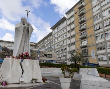 A statue of St. John Paul II, with flowers and candles at its base, is seen outside of Rome's Gemelli hospital Feb. 14, 2025, the day Pope Francis was admitted for tests and treatment of bronchitis. (CNS photo/Pablo Esparza)