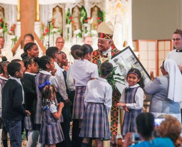 Students present then-Archbishop Wilton D. Gregory of Washington with a poster after Communion at St. Augustine Church in Washington June 2, 2019. Pope Francis named him cardinal the following year. (OSV News  photo/Andrew Biraj, Catholic Standard)