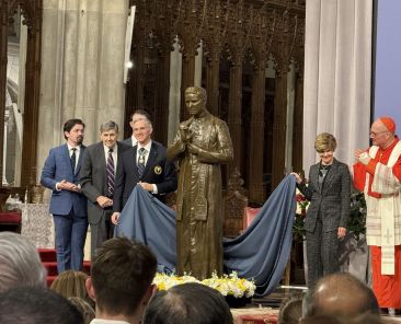 Cardinal Timothy M. Dolan of New York, right, Knights of Columbus Supreme Knight Patrick Kelly, left of statue, and members of the McGivney family unveil a bronze statue of Blessed Michael McGivney donated by the Knights of Columbus to St. Patrick's Cathedral in New York Feb. 22, 2025. (OSV News photo/Steven Schwankert, The Good Newsroom)