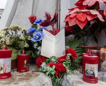 Una tarjeta de felicitación para el Papa Francisco se encuentra entre flores y velas votivas al pie de una estatua de San Juan Pablo II en el exterior del hospital Gemelli de Roma el 18 de febrero de 2025. El padre Jim Sichko, sacerdote de la diócesis de Lexington, Kentucky, dijo a CNS que había dejado la tarjeta para el Papa junto con una botella de bourbon de Kentucky, que alguien se llevó. El padre Sichko dijo que esperaba que alguien la llevara a la habitación del Papa. (Foto CNS/Pablo Esparza)