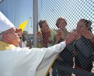 Bishop Mark J. Seitz of El Paso, Texas, is pictured in a file photo touching the hands of people in Mexico through a border fence following Mass in Sunland Park, N.M. Bishop Seitz called for a protest against Trump administration mass deportations, with the demonstration set to take place in El Paso, Texas, March 24, 2025, the feast of St. Oscar Romero, and attended by an international delegation of bishops. (OSV News photo/Bob Roller)