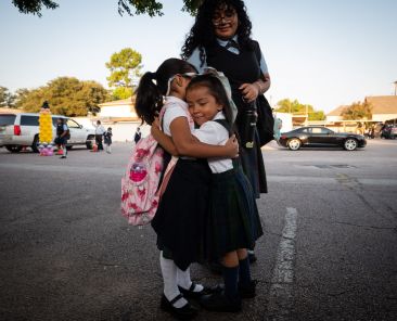 Penelope Medina, left, is hugged by friend Noemi Lujano as Audrey Medina watches, during the first day of classes at St. Mary of Carmel Catholic School in Dallas, on Aug. 8, 2025.