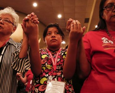 Navajo Dawn Hale, 12, of Tohatchi, N.M., holds hands with other Tekakwitha Conference attendees July 24 as they pray the Our Father during Mass in Fargo, N.D. The gathering of Native American Catholics, held July 23-27, marked its 75th anniversary. (CNS photo/Nancy Wiechec) (July 25, 2014) See TEKAKWITHA-OPENING July 25, 2014.