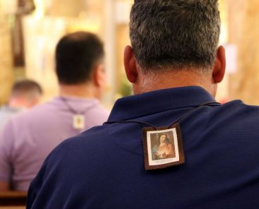 Men are seen in a file photo wearing scapulars during a Mass marking the feast of Our Lady of Mount Carmel at the Pontifical Shrine of Our Lady of Mount Carmel in East Harlem, N.Y. Wearing a Miraculous Medal or scapular in any of its various colors indirectly recalls the time-honored apparitions of the Virgin Mary in which these sacramentals find their origins. (OSV News photo/Gregory A. Shemitz)