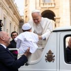 Pope Leo XIV smiles as he greets a child dressed as the pope from the popemobile while riding around St. Peter’s Square at the Vatican before his weekly general audience March 11, 2026. (CNS photo/Lola Gomez)