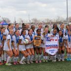 Members of the Bishop Lynch High School women’s soccer team pose with the TAPPS Division I championship banner and trophy after defeating Houston St. Agnes Academy 1-0 in overtime in the state final March 6 in Round Rock. (Bishop Lynch High School photo)