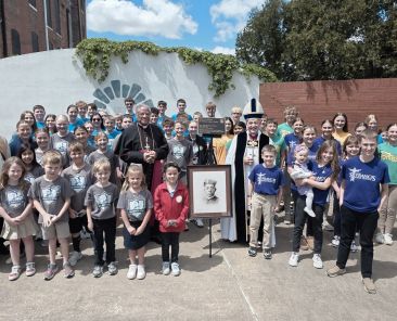 Retired Chicago Auxiliary Bishop Joseph N. Perry, center, and Bishop Thomas J. Paprocki of Springfield, Ill., wearing miter, pose with Catholic school children surrounding the plaque designating the soon-to-be shrine for Father Augustus (Augustine) Tolton in Quincy, Ill., April 29, 2026. (OSV News photo/courtesy Diocese of Springfield)