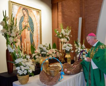 Phoenix Bishop John P. Dolan places a carnation before Our Lady of Guadalupe, the diocese’s patron saint, at the first annual Mass of Remembrance for Those Who Have Died by Suicide on Sept. 4, 2022, at Ss. Simon and Jude Cathedral in Phoenix. Family and friends were given a carnation -- one for each victim -- and lined up to place the flowers before the cathedral’s side altar. Names of the loved ones also appeared in a book before the altar. (OSV News photo/Brett Meister, courtesy Diocese of Phoenix)
