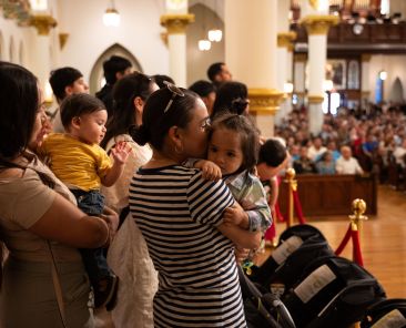 A mother kisses her child as she listens to a reading during a special Mass for Mother’s Day and Pope Leo XIV, on Sunday, May 11, 2025 at the National Cathedral Shrine of Our Lady of Guadalupe in Dallas.