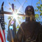 The sun shines through a statue of Christ on a grave marker alongside an American flag at St. Mary Catholic Cemetery in Appleton, Wis., in this 2018 photo. The U.S. Conference of Catholic Bishops' 2026 observance of Religious Freedom Week is June 22-29, and it is more timely than ever, Emily Schumacher-Novak, associate director of education and outreach for the USCCB's Secretariat of Justice and Peace, told OSV News. (OSV News file photo/Bradley Birkholz)