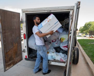 Jose Gutierrez organizes a box of diapers inside a trailer of donations for victims of the Oak Cliff apartment explosion, on Sunday, May 31, 2026 at Blessed Sacrament in Dallas.