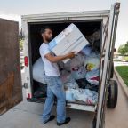 Jose Gutierrez organizes a box of diapers inside a trailer of donations for victims of the Oak Cliff apartment explosion, on Sunday, May 31, 2026 at Blessed Sacrament in Dallas.