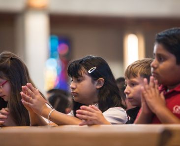 Students praying during mass on the first day of classes at Good Shepherd Catholic School in Garland on Tuesday.