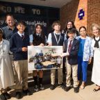 Students, faculty and the parents of Preston James, a Jesuit student who was a teacher's assistant at OLPH in Dallas but sadly passed away in 2021, participated in a butterfly release as a tribute to him on September 23rd at OLPH in Dallas. (l-r) Sister Manjula, Joe James, Benjamin Perez, Nayla Alejos, Mateo Garcia, Ms. Lambert, Johnny Avila, Maria Rodriguez and Tammie James pose with a photo of Preston James and a class of students while he was a teacher's assistant at OLPH.